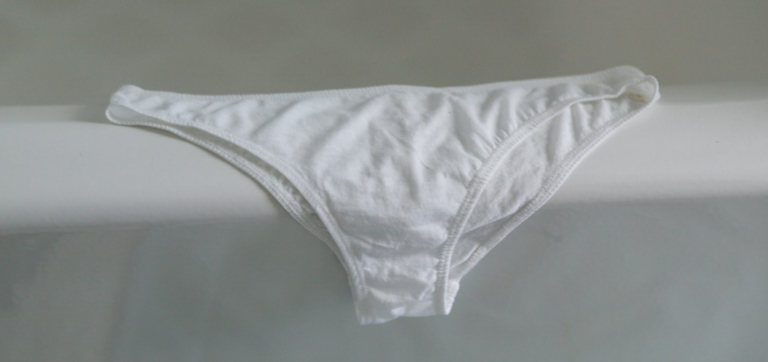 White cotton bikini-style underwear laid flat on a light surface