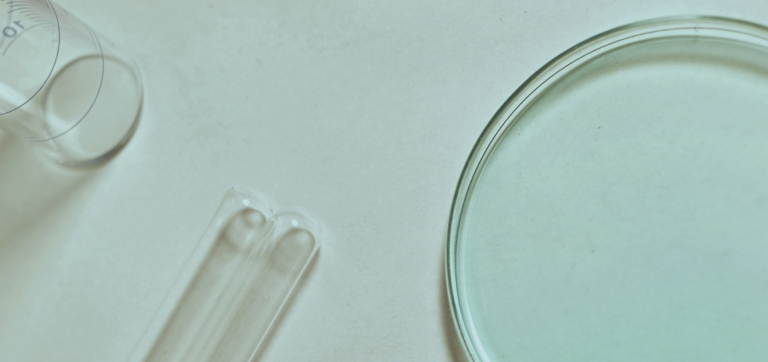Clear glass test tubes and petri dish on a light surface in a laboratory setting
