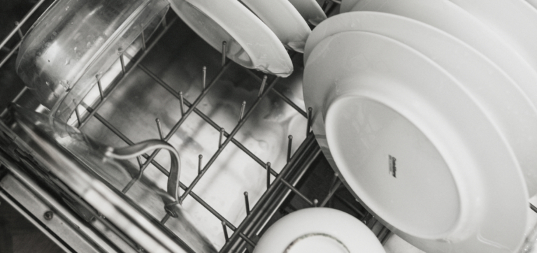 Plates and glassware arranged inside a dishwasher rack.