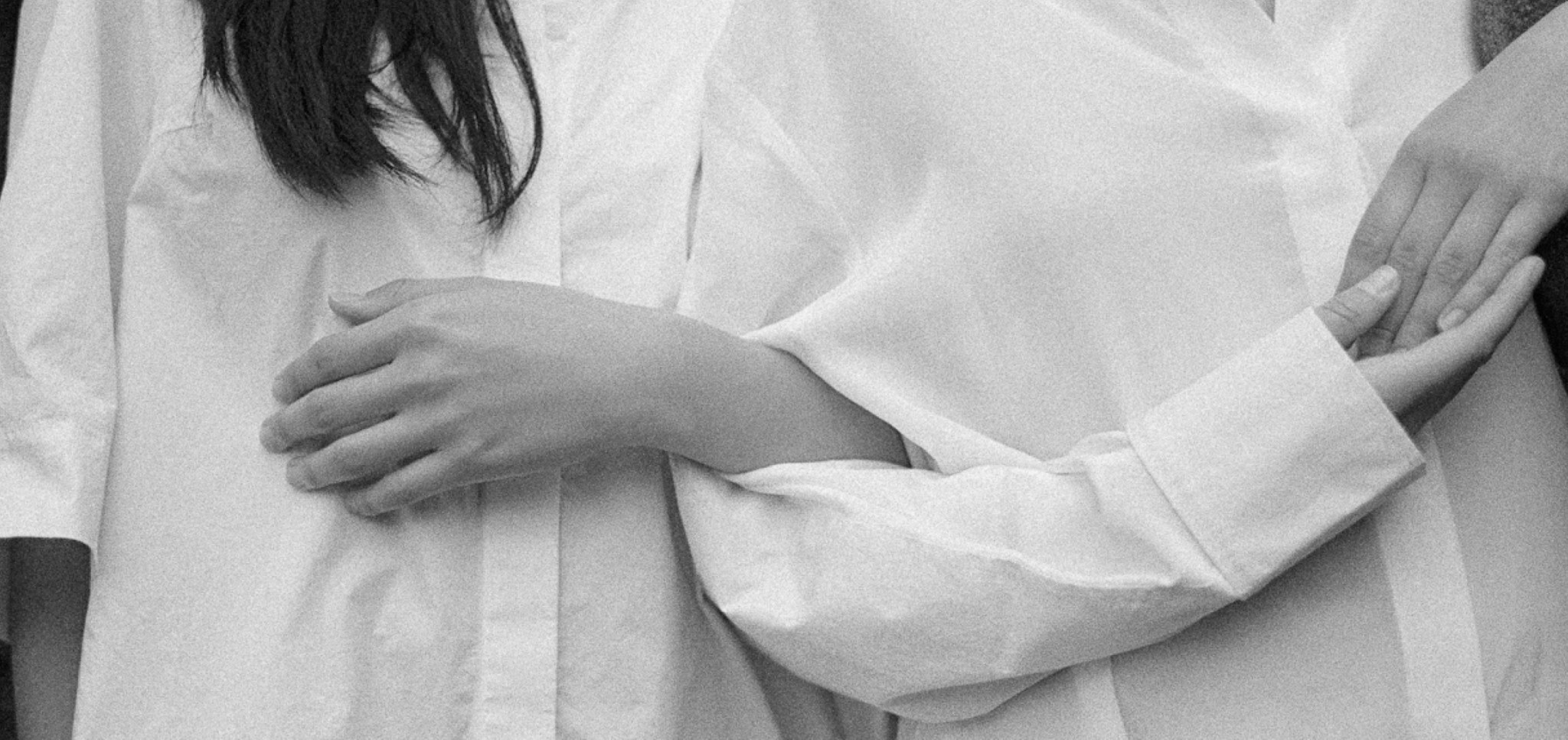 Two people in white shirts holding each other's arms in black and white photo