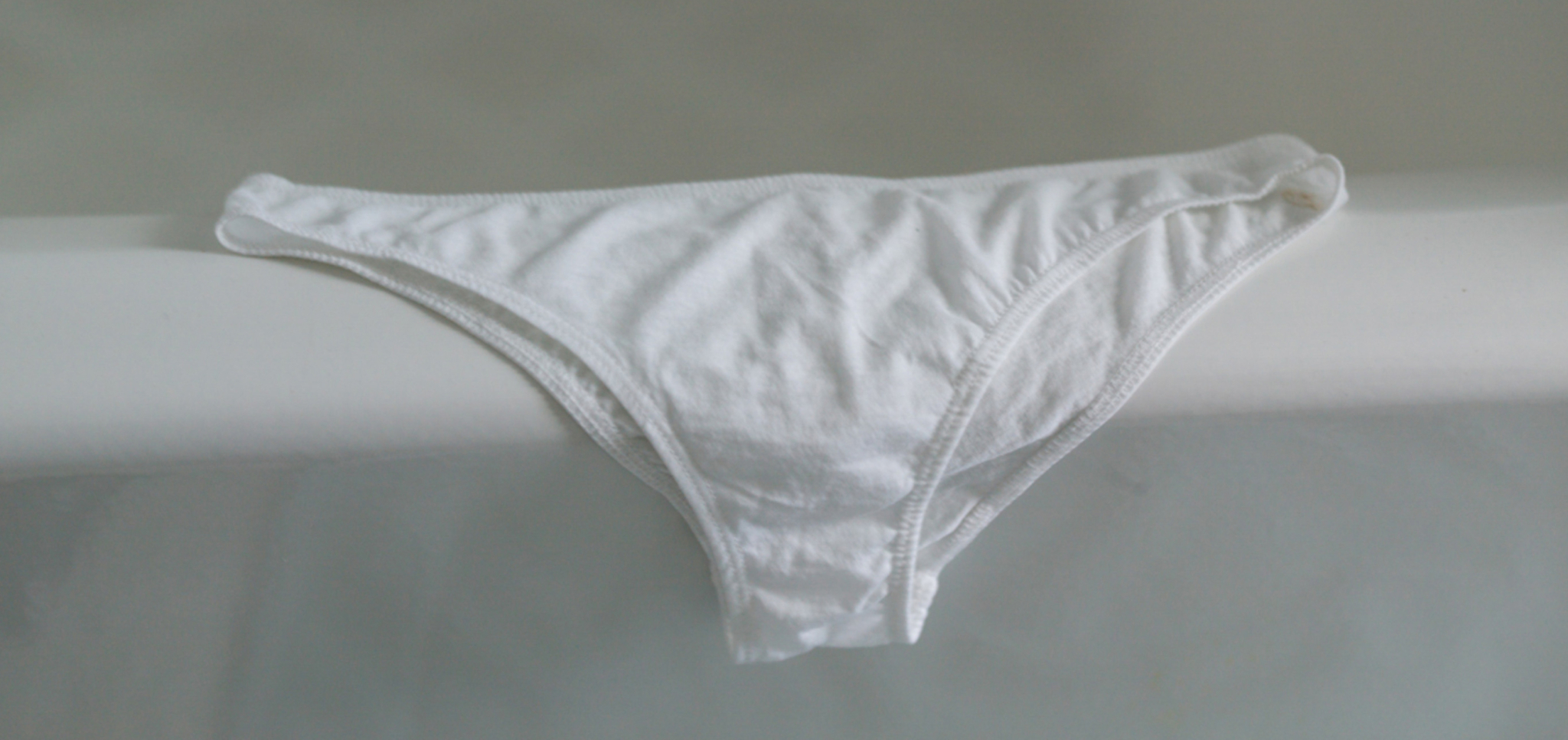 White cotton bikini-style underwear laid flat on a light surface