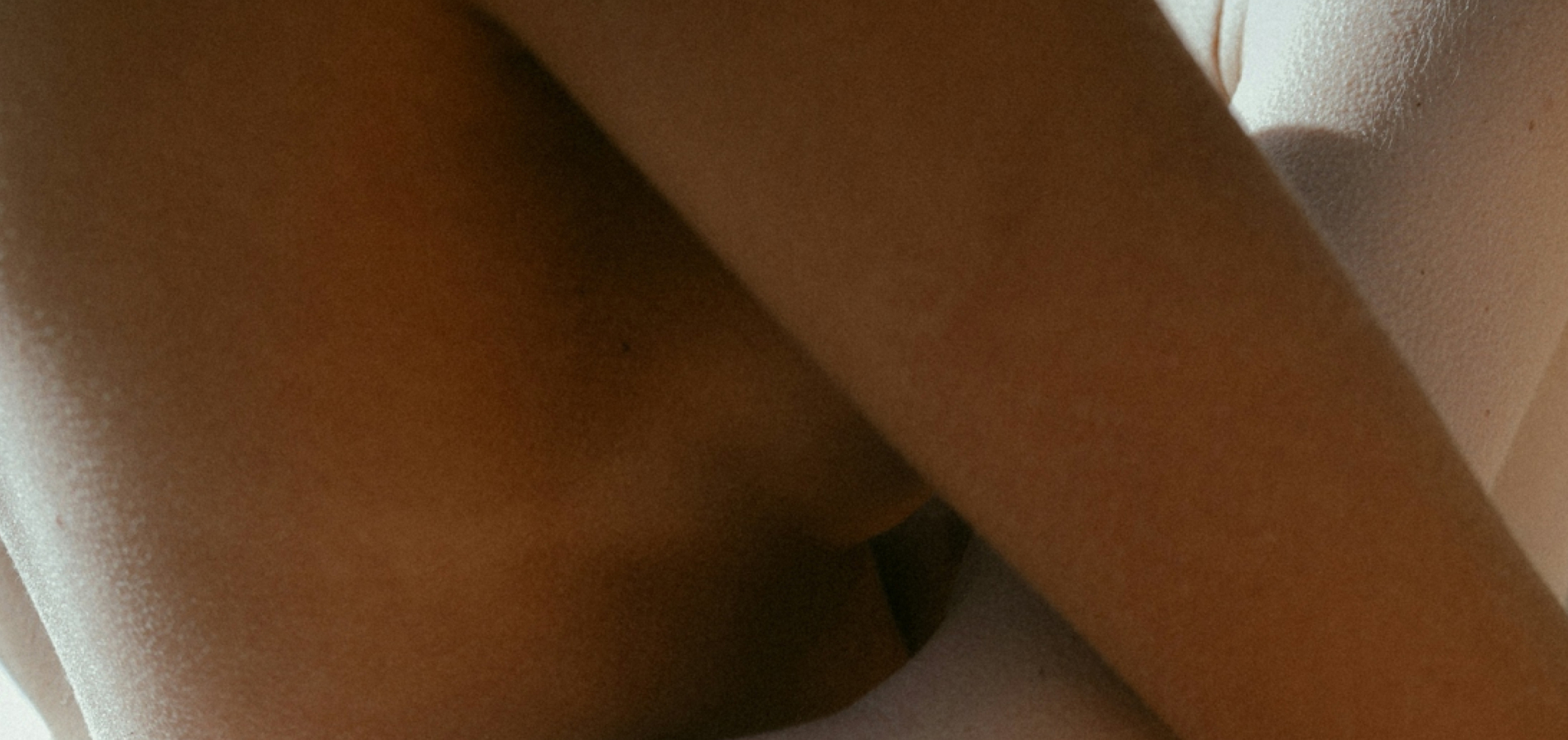 Close-up of a person's crossed arms and torso against a light background.