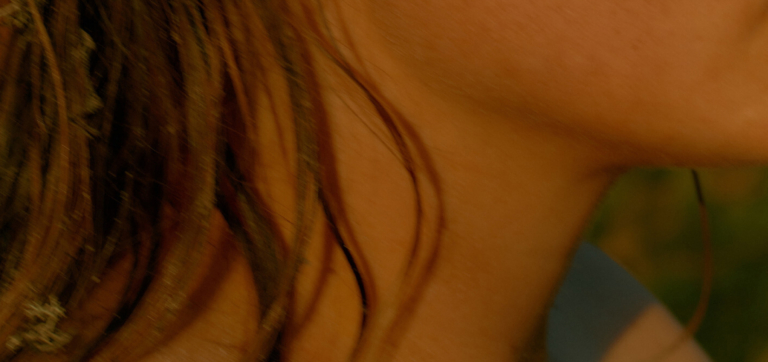 Close-up of a person's neck and hair with a blurred background.