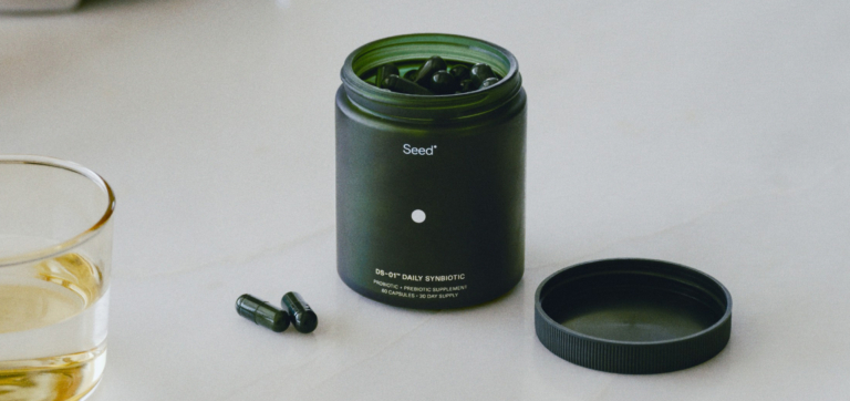 Open jar of Med-Lock probiotic capsules with two capsules and a glass of water nearby