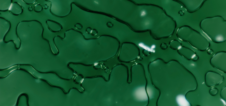 Close-up of green liquid with irregular shapes and bubbles on the surface